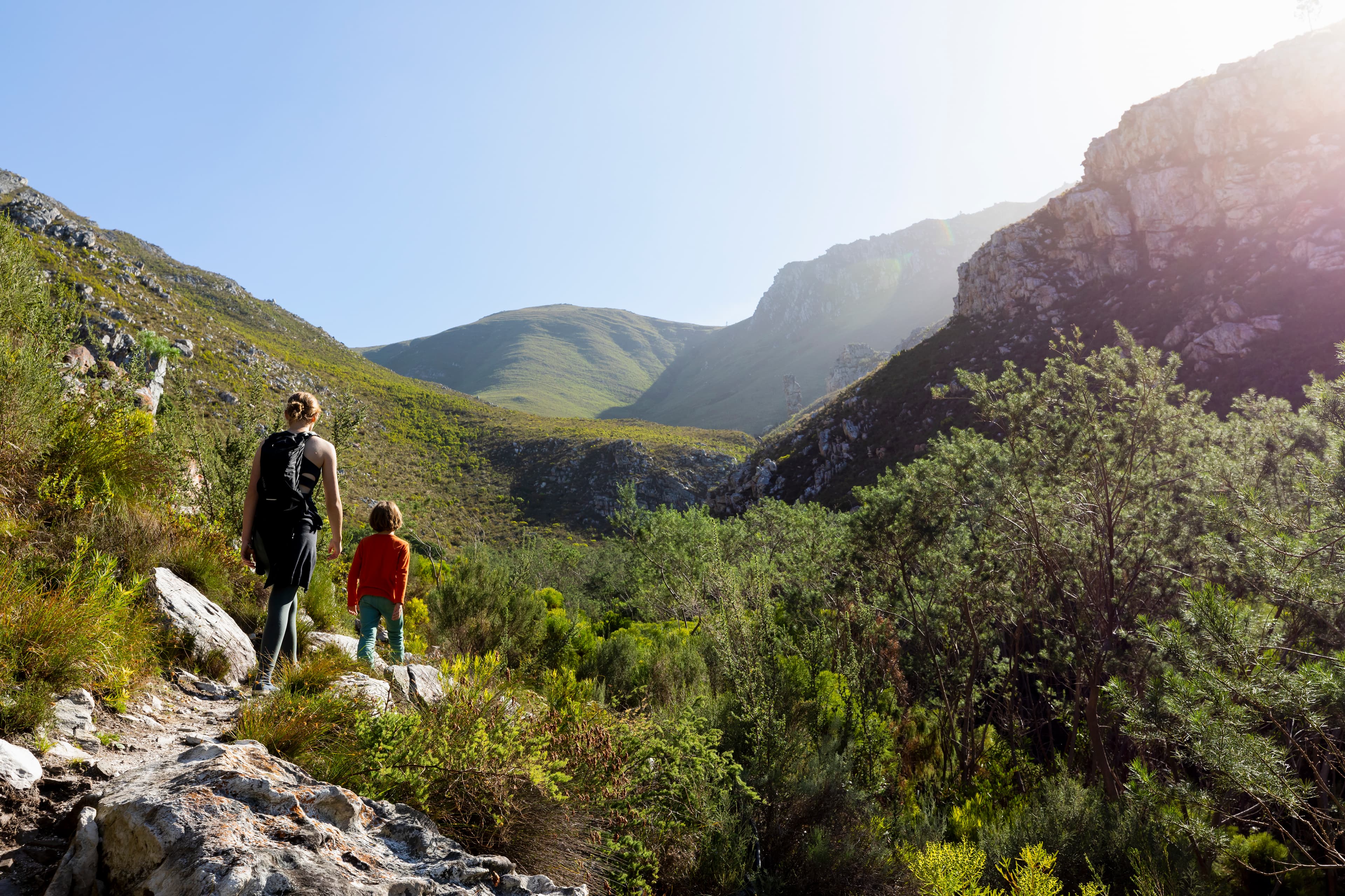 Teenage girl and younger brother hiking through a mountain valley representing normal vs optimal wellness